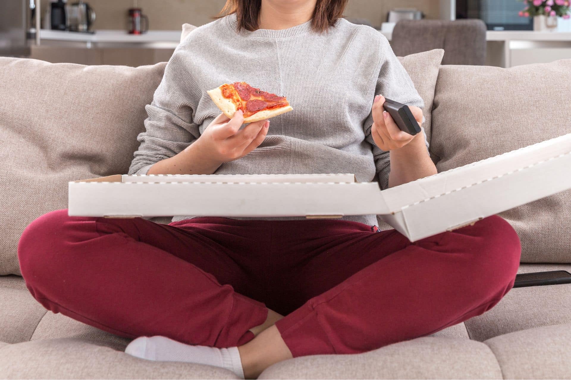 A woman sitting on a couch eating pizza